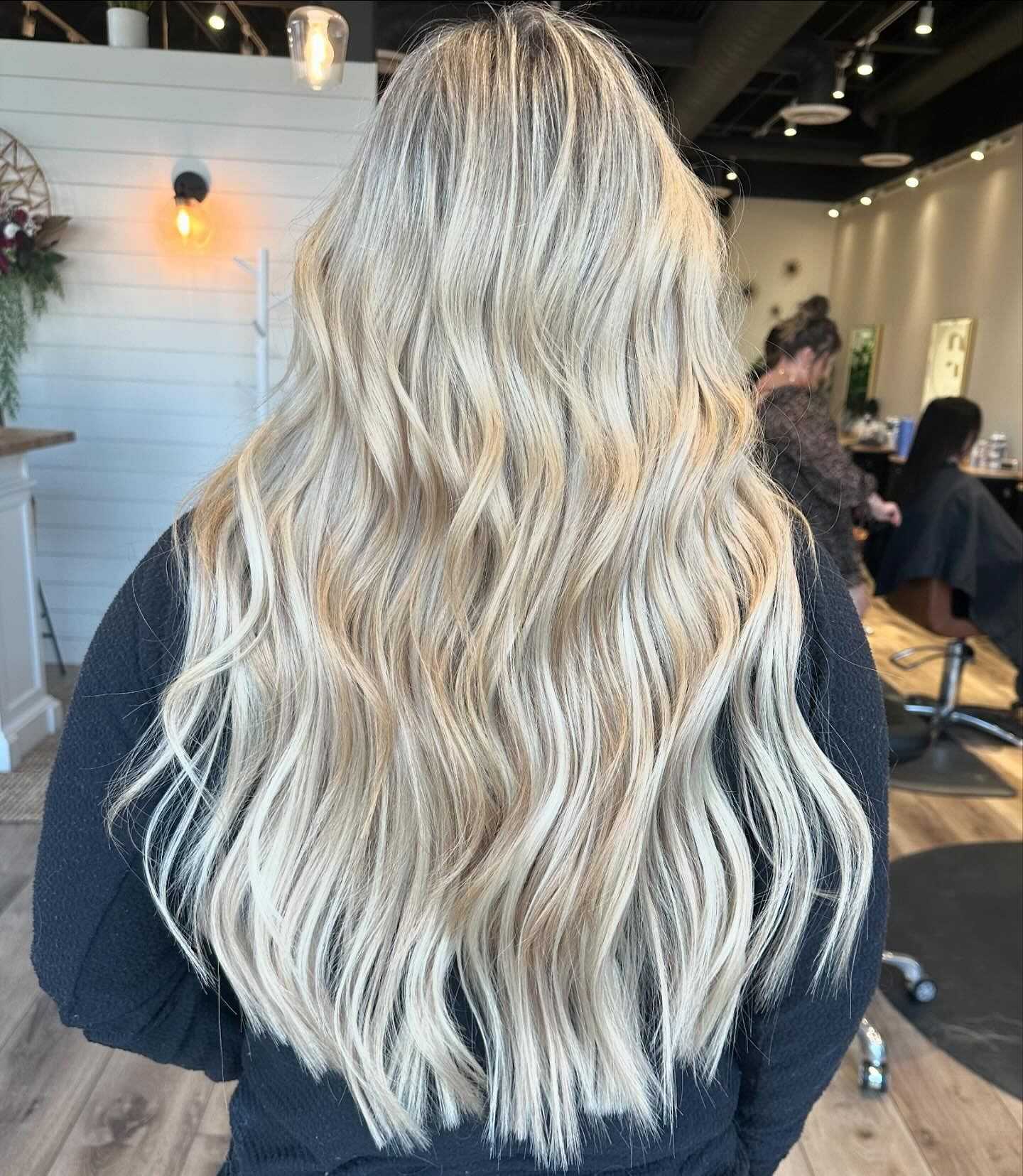 Woman with long, wavy blonde hair showcased in a salon.
